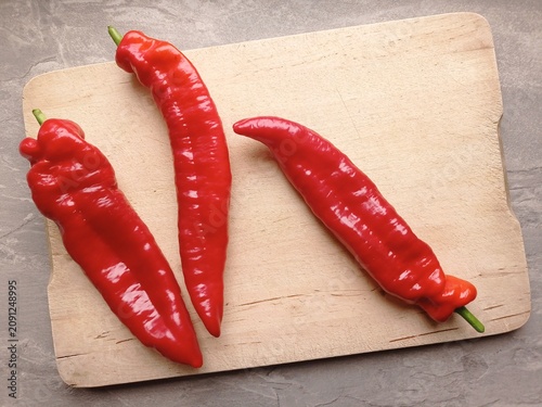 Foto Top view of three fresh sweet pointed peppers on a wooden cutting board