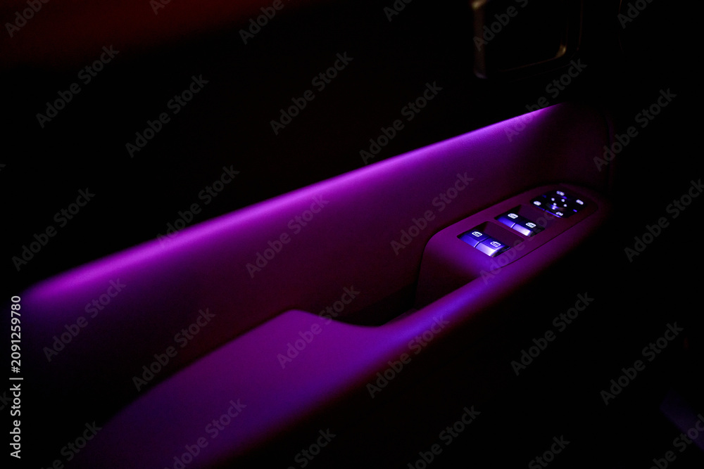 Fototapeta premium person relaxing in luxury car interior using phone with casual vibe and purple ambient lighting from passenger side view in vehicle with leather seats and wooden dashboard.