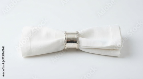 White linen dinner napkin with elegant silver napkin ring isolated on white studio background