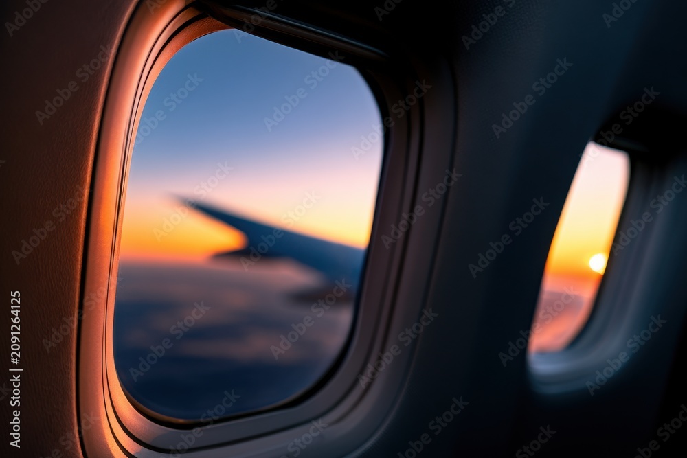 Fototapeta premium Airplane window view showing a sunset sky. Perfect for travel advertising and vacation inspiration themes.