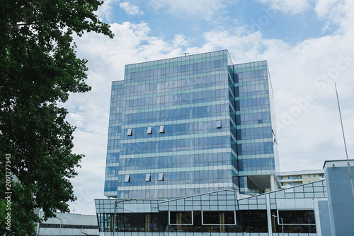 Photos Building with glass exterior stands against a cloudy sky in a city on a weekday