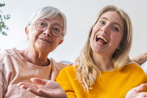 Canvastavla Grandmother and granddaughter laughing together on a couch, sharing a joyful moment of family bonding and warmth, casual indoor portrait showing affection, generation gap bridged by smile