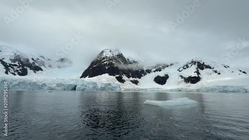 Glacier Front Beneath Cloud Covered Peaks in Paradise Bay, Antarctica