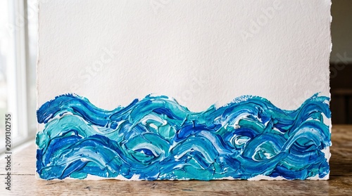 Textured blue and teal acrylic waves create a bold border along the bottom of white watercolor paper, shot on a rustic wooden table with generous copy space for coastal branding, posters.