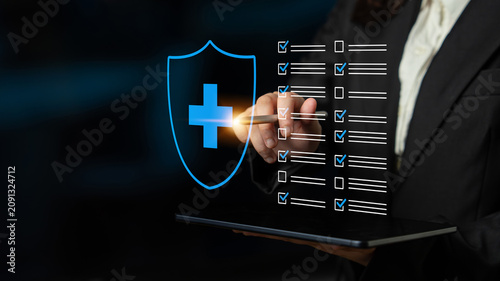 Fotografie A business professional examines a health insurance checklist on a digital tablet, emphasizing the importance of risk management and compliance in healthcare and corporate environments