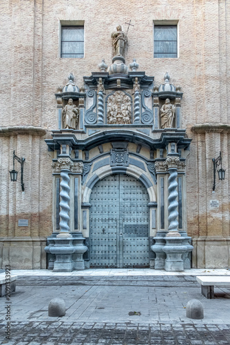Baroque portal of the San Felipe y Santiago el Menor Church in Zaragoza. Ornate stone entrance with twisted columns and religious statues in the historic center. Zaragoza, Spain - November 29, 2021