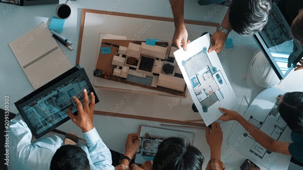 Obraz premium Top down view of manager pointing at house model and explain building design. Aerial view of architect engineer brainstorming about interior construction while tablet display house plan. Alimentation.