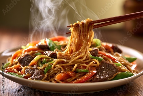 Plate of beef lo mein noodles with glossy sauce, steam, and chopsticks