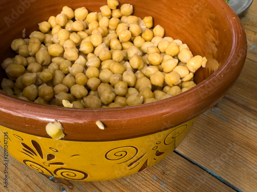 Boiled yellow chickpeas served in a traditional Greek ceramic bowl on a rustic wooden table. Authentic Mediterranean vegan food preparation in Crete, Greece.