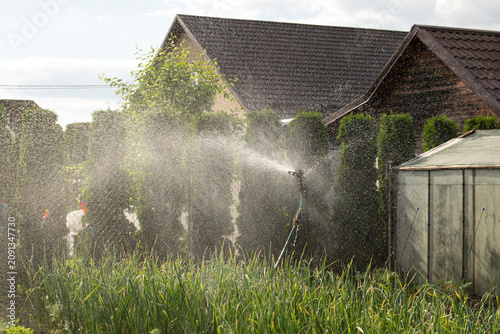 Construction for watering the soil and green spaces. Agricultural crops grow in an individual garden. The territory is watered to improve plant growth.
