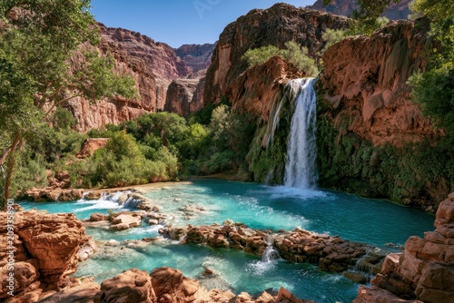 Sunlit canyon waterfall scene with emerald pools, towering red cliffs, and lush vegetation
