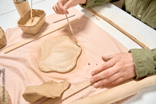 Φωτογραφία Artisan applying slip to a clay slab before attaching a coil