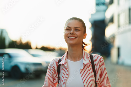 Canvas Print Smiling woman with striped shirt strolling along an urban street during daytime