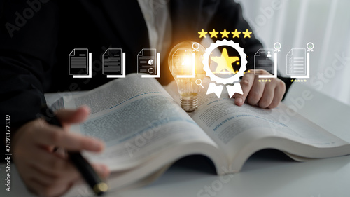 Fotografie Person in a suit studying a book with light bulb and awards symbolizing knowledge, learning, and achievement in a modern workspace Fluxor
