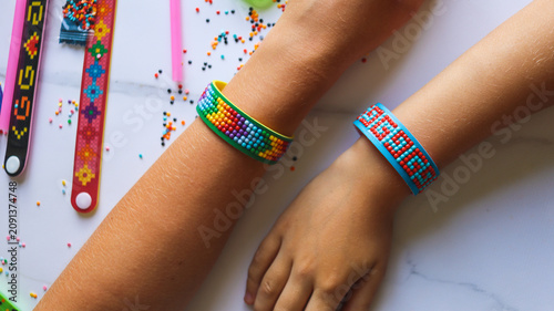 A close-up of finished handmade diamond mosaic bracelets on unrecognizable children's hands