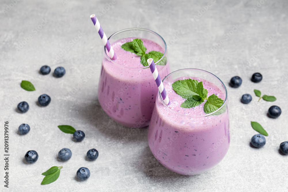 Fototapeta premium Tasty smoothie in glasses, fresh blueberries and mint on grey table, closeup