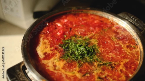 Traditional Ukrainian borscht soup with fresh dill in a metal pot cooking close up