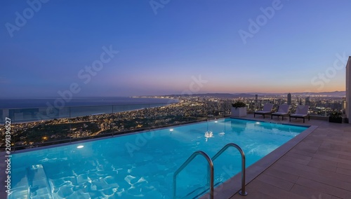 Sunset at a Luxury Pool Overlooking a City and Ocean, During Twilight Hours N...