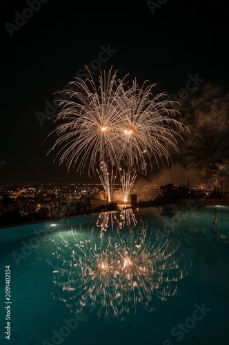 Fireworks Display Over a Swimming Pool at Night With Reflections in the Water
