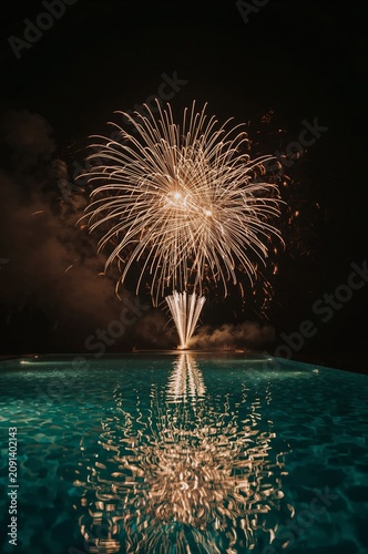 Fireworks Display Over a Swimming Pool at Night With Reflections in the Water