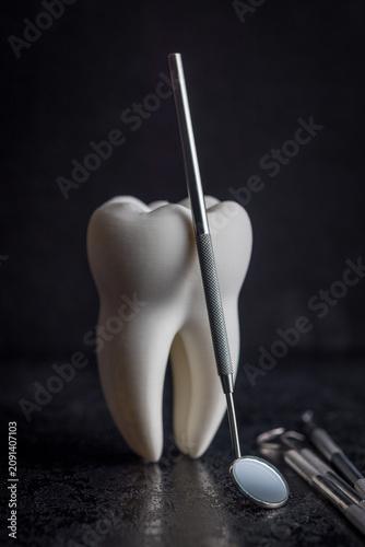 Dental Tooth Model With Stainless Steel Dental Tools and Mirror on Dark Background for Dentistry