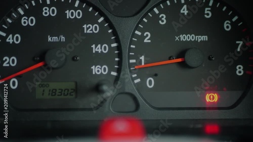 Close-up of car dashboard with red brake warning light illuminated. Vehicle safety and maintenance concept.