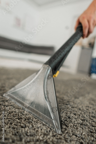 Fotografía Carpet cleaning extractor nozzle lifting dirt from gray carpet in bright indoor