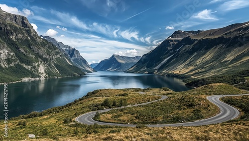 Winding Road Along a Lake and Mountains Under a Blue Sky With Clouds in Norway