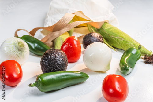 Fresh organic mexican vegetables spilling from a reusable grocery bag