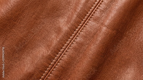 Detailed close up view of premium brown leather material featuring strong durable stitching lines running diagonally across the textured surface