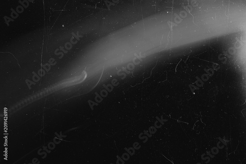 Cinematic black and white film damage overlay with diagonal light flare and dust