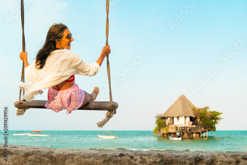 Photos Happy excited traveler woman relaxing on swing above south beach in Zanzibar