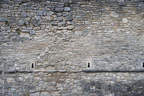 Photos the weathered, rustic stonework of Zbarazh Castle's defensive walls, highlighting the texture and the small, narrow loopholes used for defense