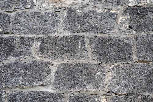 Foto a weathered, dark grey stone wall featuring roughly hewn rectangular blocks and light grey mortar