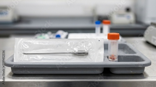 Muscle biopsy Bergstrom needle in sealed sterile packaging beside a specimen transport container on a sports science research tray
