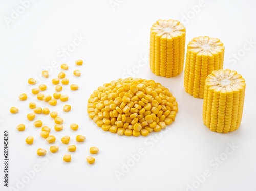 A clean studio shot of bright golden sweet corn cobs and loose kernels, showcasing fresh agricultural produce for healthy diet designs.