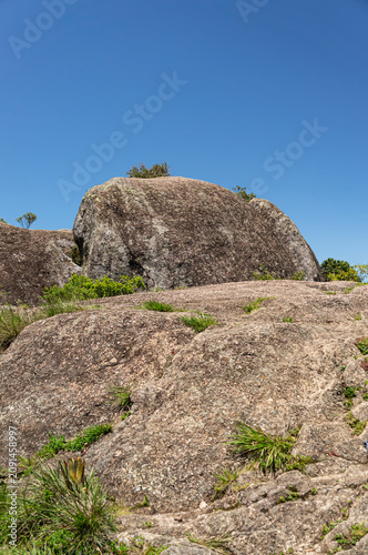 Granite rock formations at Pedra Redonda summit with native green vegetation natural landscape under summer morning sunny clear blue sky day in Monte Verde, Camanducaia, Minas Gerais, Brazil.