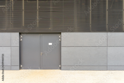 Modern grey facade with closed double entrance doors and industrial cladding panels on a contemporary building exterior
