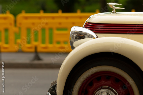 Obraz na plátne Partial view of a cream-colored classic automobile showing the front fender, red