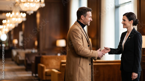 Smiling Luxury Hotel Receptionist Shaking Hands Welcoming Male Guest in Elegant Lobby for Premium Hospitality, Concierge Service, Customer Care, and Business Travel Concept