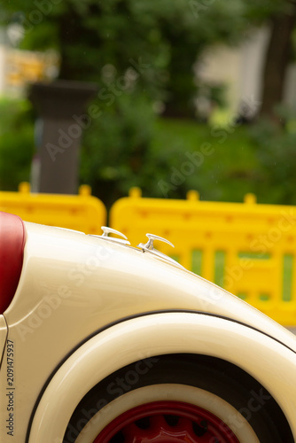 Foto Close-up of the rear section of a cream-colored vintage car showing the curved fender, red leather seat edge and whitewall tire