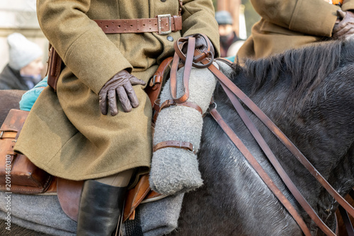 Fotografie Anonymous cavalry soldier in vintage uniform riding dark horse, closeup of leath