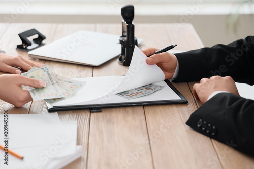 Tableau sur toile Hands exchanging money and documents on a wooden desk bribery corruption and ill