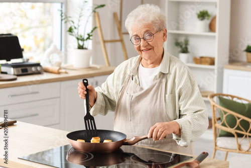 Senior woman frying cottage...
