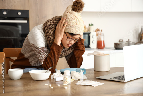 Ill Asian man in kitchen