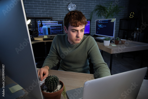 Male programmer working with laptop in office at night