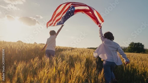 Cute little boys - American patriot kids running with national flag on open area countryside road.USA, 4th of July - Independence day, celebration. US banner,memorial Veterans,election.