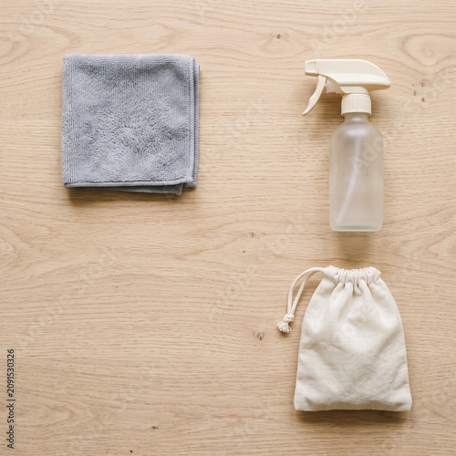Eyeglass cleaning cloth and spray bottle flat lay on a wooden table, blank product mockup