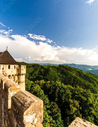 Stone Castle Tower Overlooking Lush Green Forest Valley Under Blue Sky
