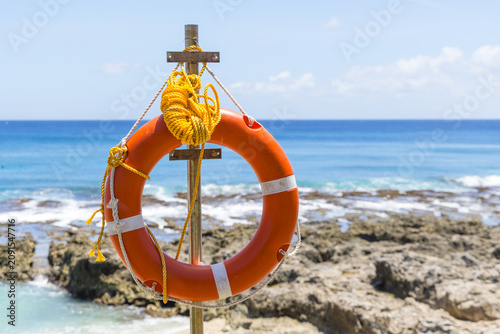 Orange lifebuoy by the tropical ocean